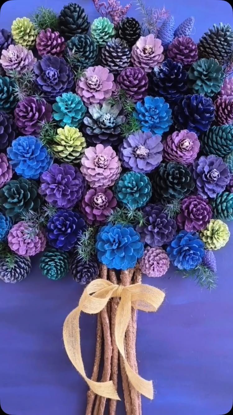 Painted pinecones in purple, blue, and green tied with a yellow ribbon.