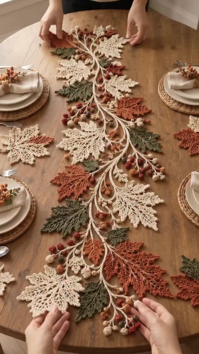 Crocheted autumn leaf table runner in orange and green on a wooden table.