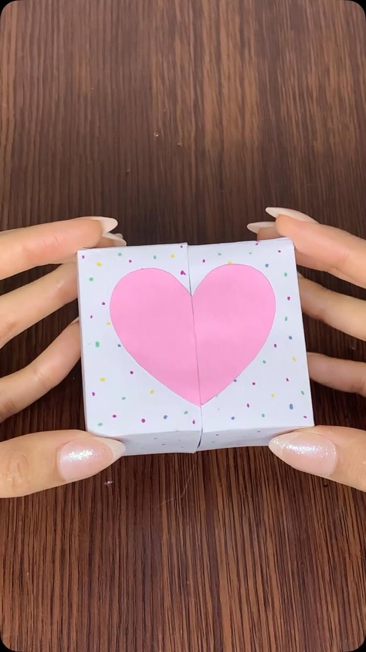 Small white gift box with a pink heart and colorful confetti dots.