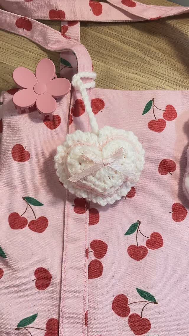 White crocheted heart with pink bow on a cherry print pink bag