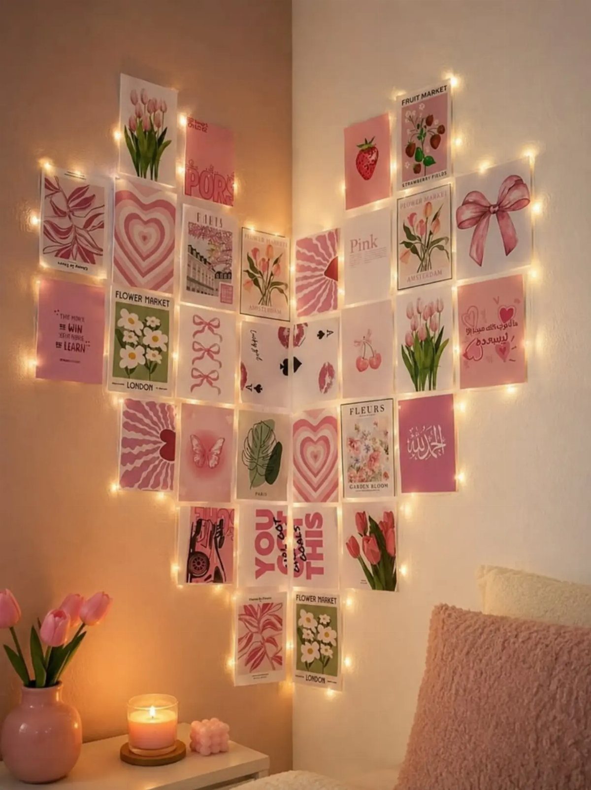 Heart-shaped arrangement of pink aesthetic postcards on a wall with fairy lights.