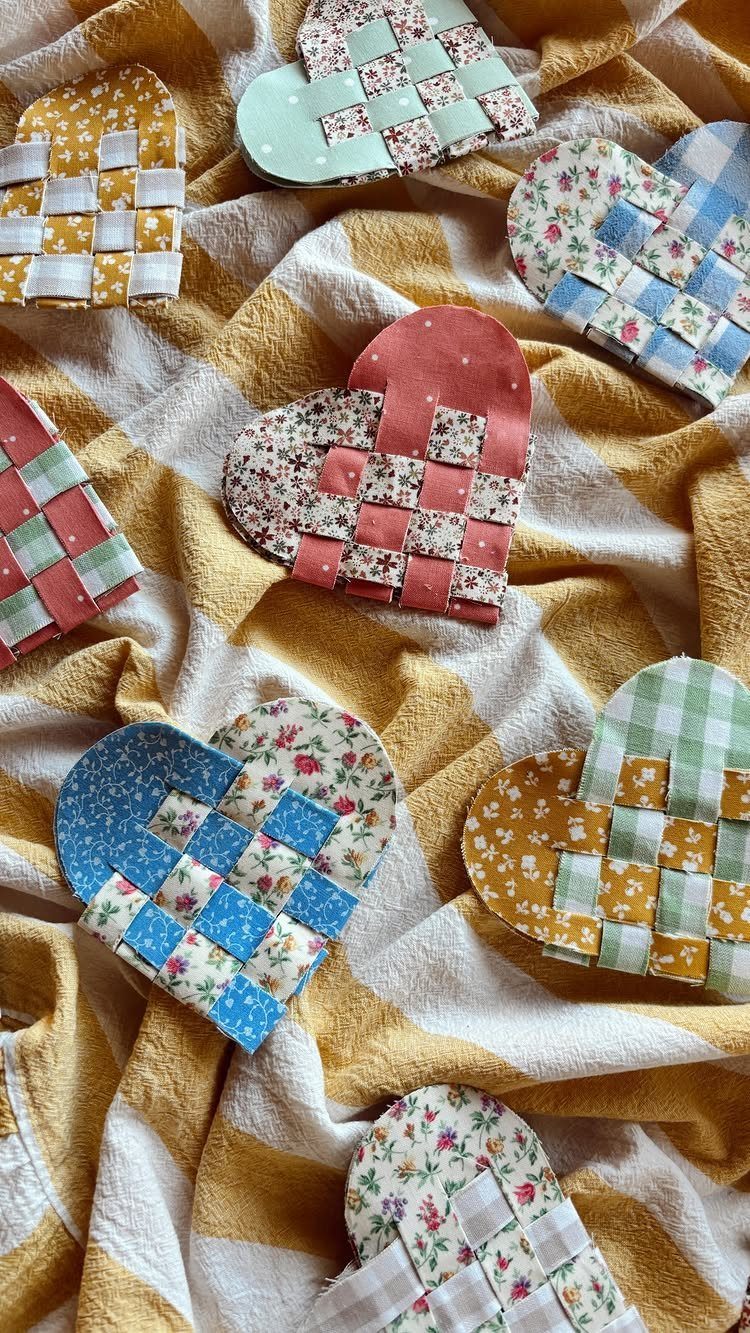 Heart-shaped fabric crafts with woven colorful patterned strips on striped yellow cloth.