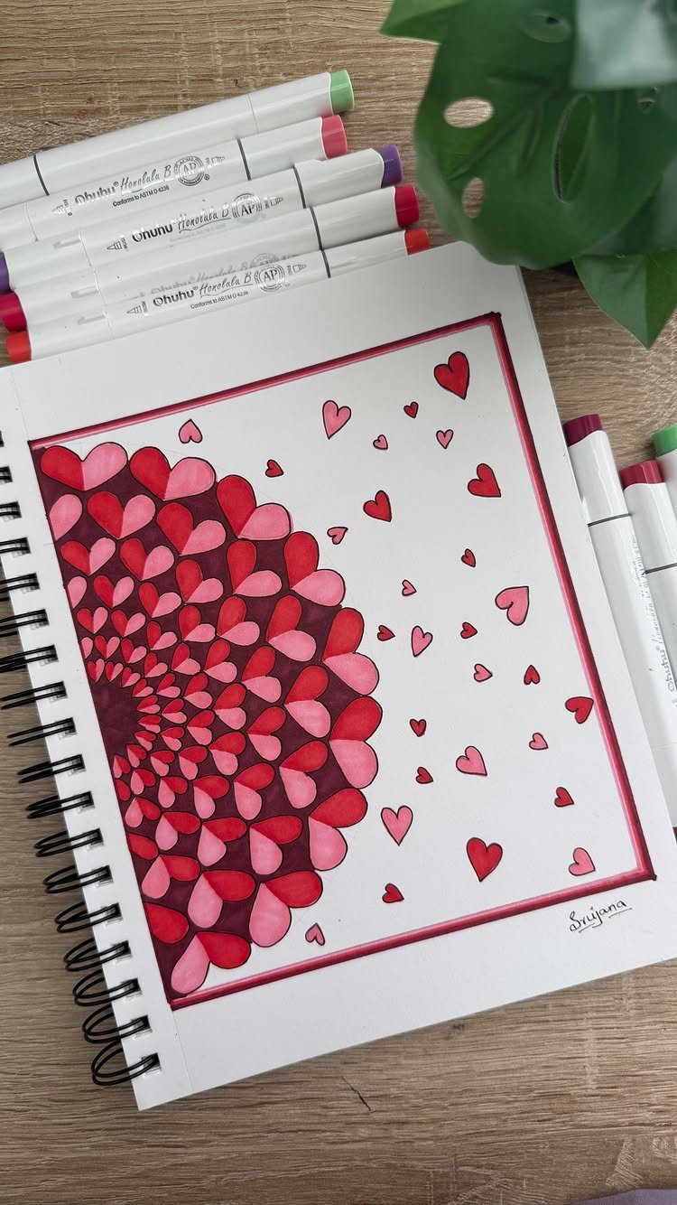 Heart-shaped mandala drawing in red and pink markers inside a spiral notebook.