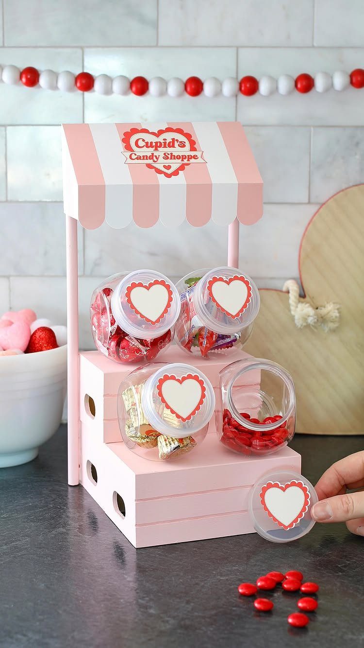 Pink Cupid's Candy Shoppe stand with jars of red sweets and heart lids.