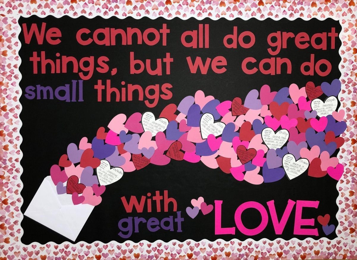 Valentine bulletin board with a white envelope and colorful paper hearts flowing out.
