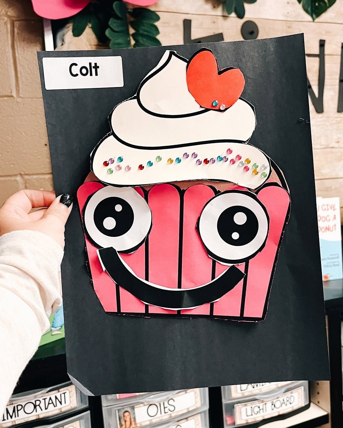 Paper cupcake craft with a red heart and smiling face on black paper.