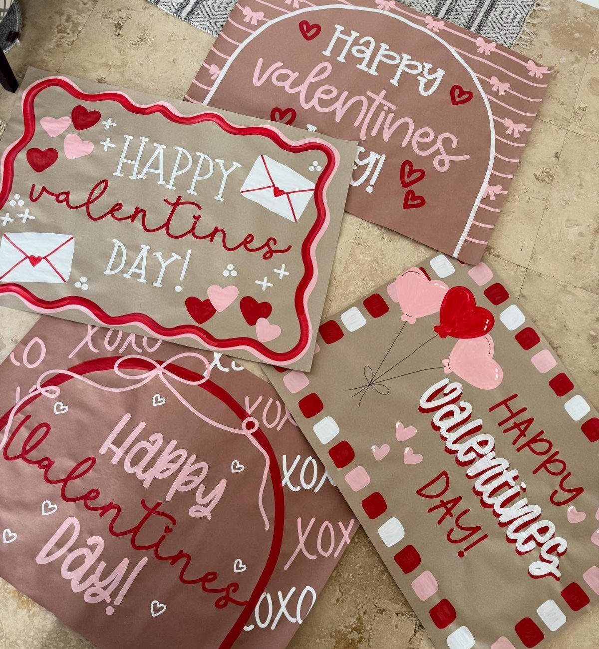 Hand-painted Valentine's Day posters with red and pink hearts on brown paper.