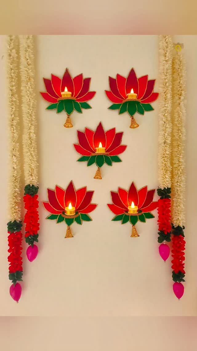 Lotus-shaped wall decorations with lit diyas and floral garlands on a white wall