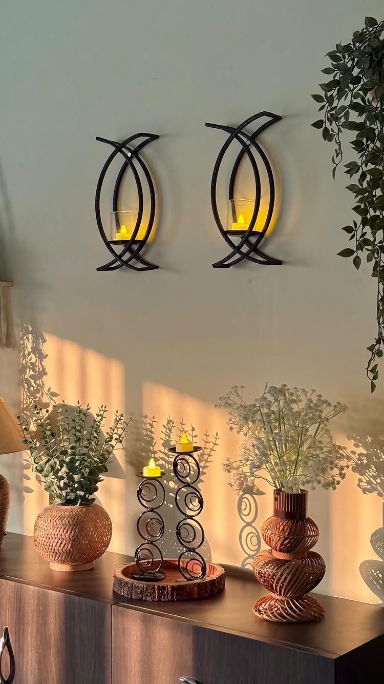 Black metal wall sconces with glowing candles mounted on a white wall
