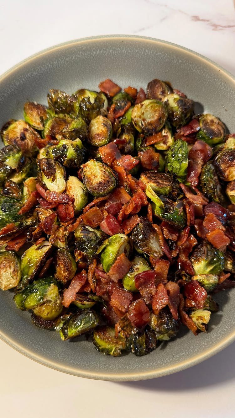 Roasted brussels sprouts with crispy bacon bits in a grey ceramic bowl.