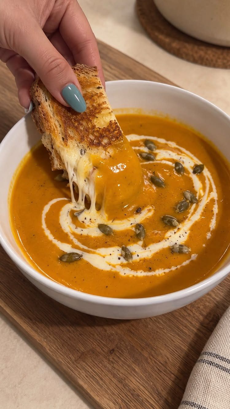 Orange butternut squash soup with cream swirl and seeds, dipped with cheesy toast.