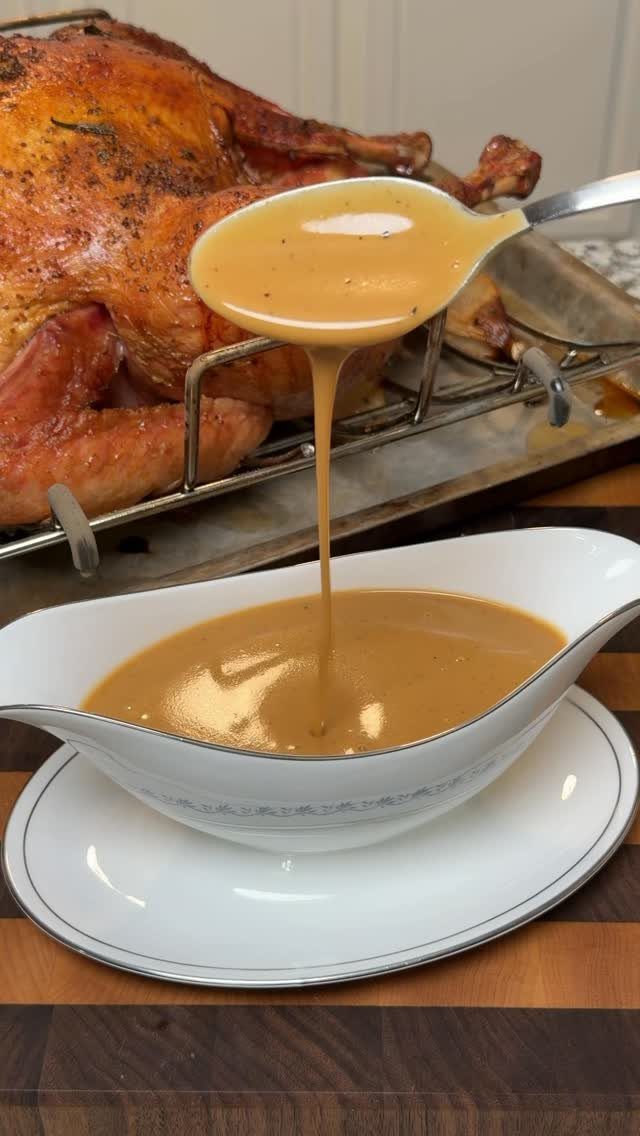 Brown gravy being poured from a ladle into a white gravy boat.