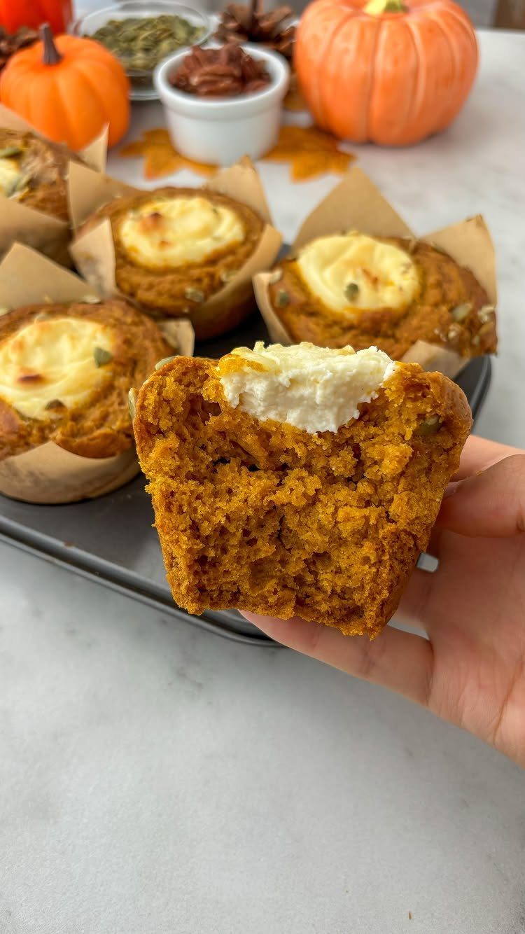 Pumpkin muffins with cream cheese frosting and small decorative pumpkins in background