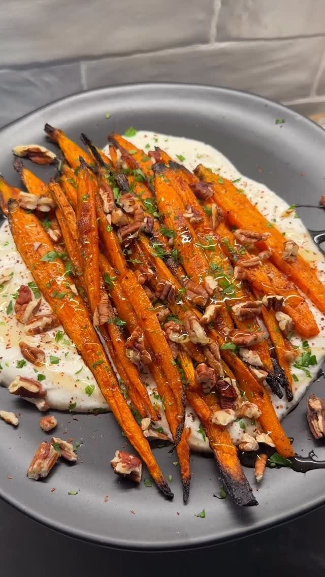 Roasted carrots with pecans and herbs over a creamy white sauce on a plate
