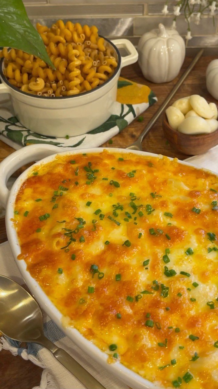 Baked macaroni and cheese with melted golden cheese and chives in a white dish.