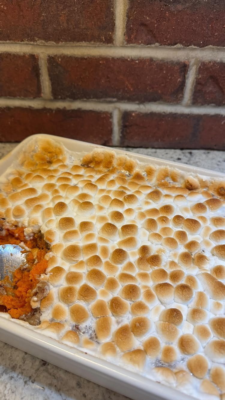 Sweet potato casserole with toasted marshmallow topping in a white baking dish.