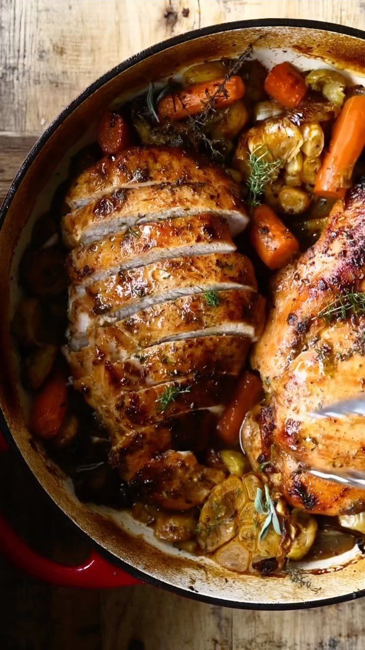 Roasted turkey breast and whole turkey with carrots in a red pot.