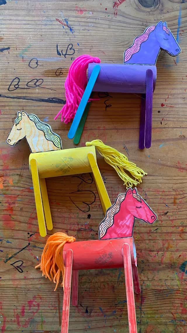 Three colorful handmade horses made from cardboard tubes, popsicle sticks, and yarn.