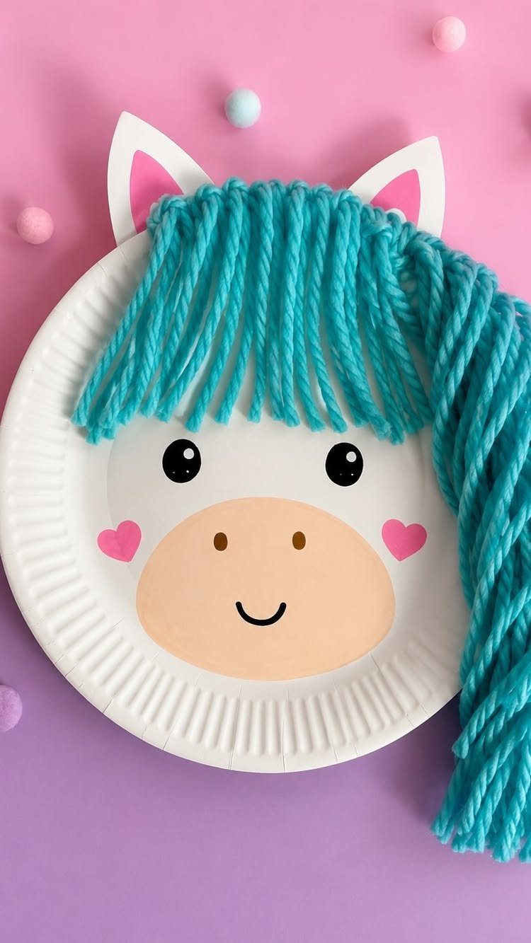 Horse face craft made from a white paper plate with teal yarn mane.